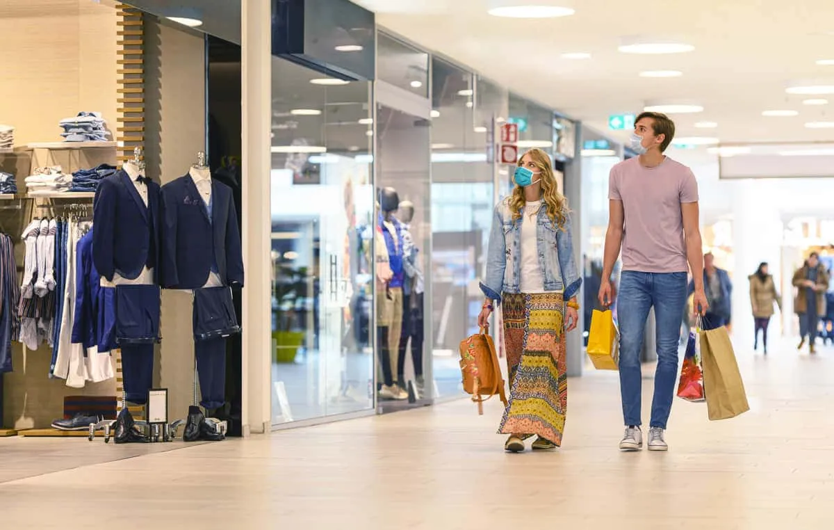 Masked shoppers walking through a clothing mall