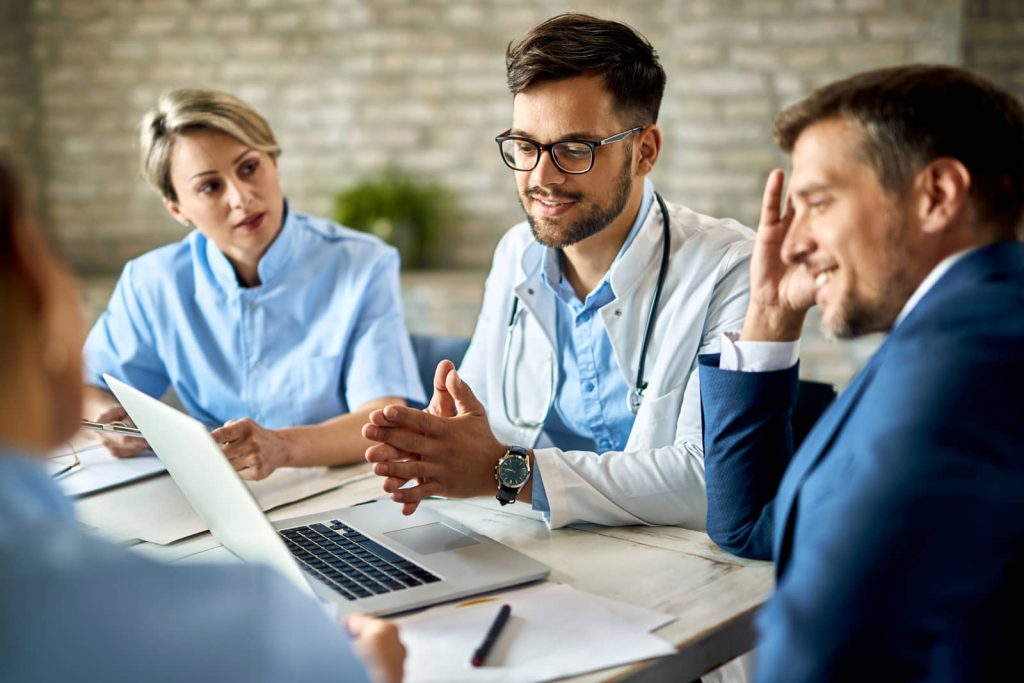 Three healthcare workers seated around a laptop