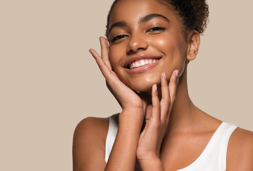 Smiling woman with clear skin touching her face